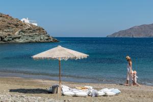 基斯诺斯Eneos Kythnos Beach Villas-Executive and Premium Villas的一名妇女和一个儿童站在海滩上,并有一把遮阳伞