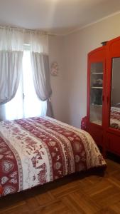 利莫内皮埃蒙特Appartamento Limone Piemonte的一间卧室配有一张带红色梳妆台和窗户的床。
