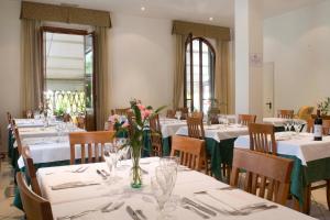 维亚雷焦维多利亚酒店的餐厅设有白色的桌椅和鲜花