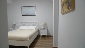 塞维利亚Living Triana House的白色卧室配有白色的床和两盏灯。
