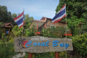 俊穆岛Koh Jum Coral Bay Resort的当地海湾度假胜地前方的标志,有两面旗帜