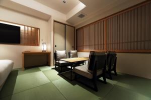 东京PROSTYLE RYOKAN TOKYO ASAKUSA的酒店客房配有桌椅和电视。