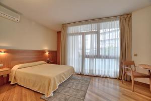 圣地亚哥－德孔波斯特拉PR罗莎旅馆的一间卧室配有一张床、一张书桌和一个窗户。