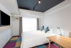 东京东京目黑佑天寺酒店的卧室配有白色的床和木桌