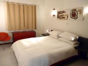 卡武埃鲁Casa Julio的卧室配有白色的床和红色椅子
