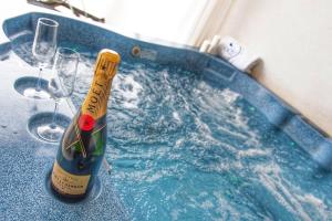 博尔塞纳Ludwig Boutique Hotel & Spa的一瓶香槟酒,在浴缸内,配以酒杯
