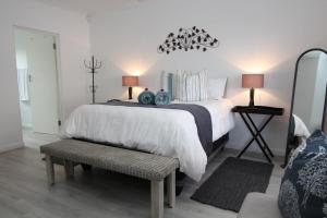 阿尔弗雷德港Beach Break B&B - Solar Powered的一间卧室配有一张白色的床、一张长凳和两盏灯。