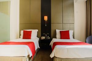 达累斯萨拉姆Onomo Hotel Dar es Salaam的酒店客房 - 带两张带红色枕头的床