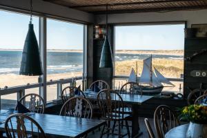 克利特默勒Klitmøller Hotel的一间带桌椅的餐厅,享有海滩美景