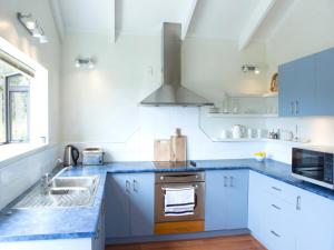 欧尼坦基Two Rooms Onetangi - Onetangi Holiday Home的厨房配有白色橱柜和蓝色台面
