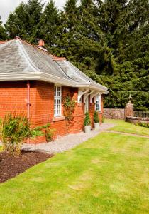 邓布兰The Gardener's Cottage的一座红砖房子,有草地庭院