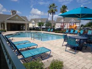 基西米True Happiness, Housing Near Disney Word的一个带蓝色椅子和桌子的游泳池以及遮阳伞