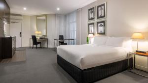 墨尔本Oaks Melbourne on Collins Suites的酒店客房设有一张大床和一张书桌。