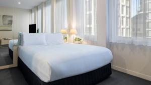 墨尔本Oaks Melbourne on Collins Suites的窗户客房内的一张大白色床