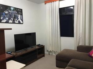 库里提巴Quarto aconchegante nas Mercês的客厅配有平面电视和沙发。