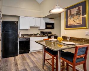坦帕Chase Suite Hotel Rocky Point Tampa的厨房配有黑色冰箱和桌椅