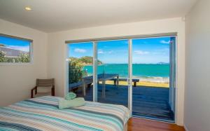 图图卡卡Shoreside - Tutukaka Holiday Home的一间卧室配有一张床,享有海景