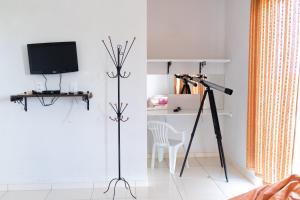 Resende CostaPousada DDB的客房设有三脚架、电视和桌子
