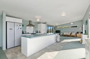 怀普The Blue Cottage with WiFi- Waipu Holiday Home的配有白色家电的厨房和客厅
