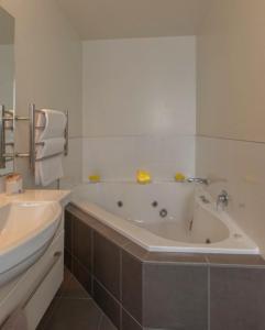 基督城棕榈机场汽车旅馆的白色的浴室设有浴缸和水槽。
