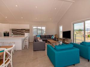 怀蒂昂格Tattletails Rest - Whitianga Holiday House的一间带蓝色沙发的客厅和一间厨房