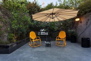 墨西哥城Casa 9的庭院里设有两把椅子和一张桌子及一把遮阳伞