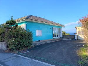 鹿儿岛GANADAN Cottage的前面有车道的蓝色房子