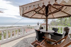 班图尔Adinda Beach Hotel and Villa的阳台配有桌椅和遮阳伞