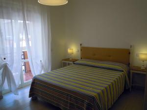 加利波利B&B Palazzo Belvedere的一间卧室配有一张带条纹毯子的床和窗户