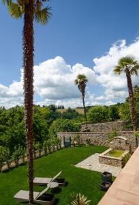 埃尔萨谷口村帕拉佐帕齐尼酒店的一座种有棕榈树和石墙的花园