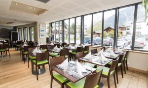 夏蒙尼-勃朗峰兰彻斯酒店的餐厅设有木桌、椅子和窗户。