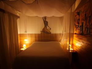 阿姆巴托洛阿卡MADIROKELY HOUSE Nosy Be的卧室配有一张床,墙上挂着女人的雕像