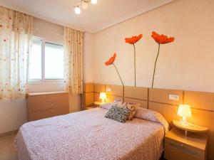 博尔瑟拉尔Apartment Jardines del Mar - Azahar by Interhome的卧室配有一张墙上有三朵花的床
