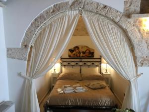 阿尔贝罗贝洛Il Trullo dei Sogni的一间卧室配有带窗帘的天蓬床