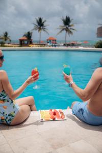 圣佩德罗格兰德加勒比伯利兹度假村的两人坐在游泳池旁,享用食物和饮料