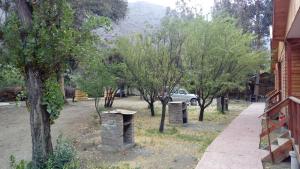 圣何塞德迈波Cabañas y Hotel Rural Mirador del Maipo的一座有树木和汽车的院子