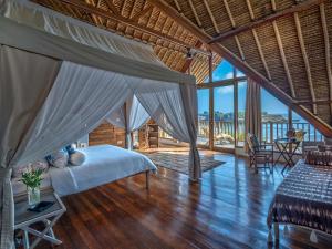 蓝梦岛Villa Voyage的一间卧室设有一张天蓬床和木地板。