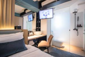新加坡Hotel NuVe Elements的一间卧室配有一张床、一张书桌和一台电视。