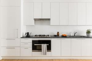 华盛顿 Liz by Black Swan - DC Executive Flat的厨房配有白色橱柜和炉灶。