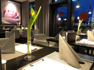 博宾根申普酒店的一间设有桌椅的餐厅和一个种植了植物的花瓶