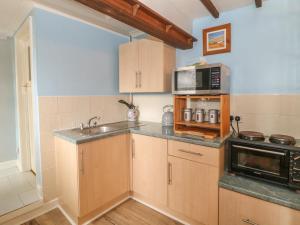 HenstridgeFrodos的厨房配有木制橱柜、水槽和微波炉