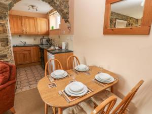 RochEynons Cottage的厨房以及带木桌和椅子的用餐室。