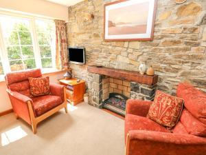 RochEynons Cottage的客厅配有两把椅子和石头壁炉