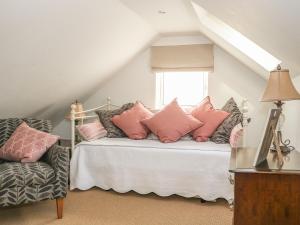 SlindonWoodend Annexe的一间卧室配有带粉红色枕头的床和窗户。