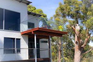 比那隆湾BAY OF FIRES BEACH SHACK ocean views from a modern Beachhouse的一座带甲板和树的房子