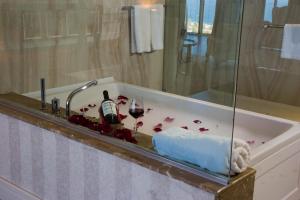 巴统Euphoria Batumi Convention & Casino Hotel的浴缸配有葡萄酒瓶和酒杯