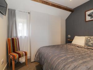 SunbrickThe Granary Loft的一间卧室设有一张床、一个窗口和一把椅子