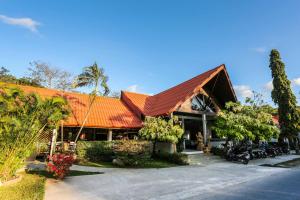 奈汉海滩Naiharn Beach Resort - SHA Plus Extra的一座建筑,前方有橙色屋顶,摩托车停放在