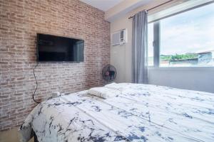 Taytay1BR Interiored Condo with WiFi, Netflix, Hot Shower - The Hive Residences的卧室配有1张床和1台砖墙电视