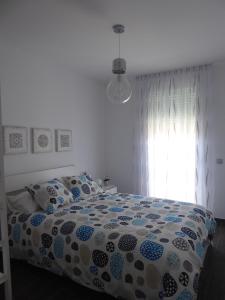拉拉古纳NORASUITES32的一间卧室配有一张带床罩的床和窗户